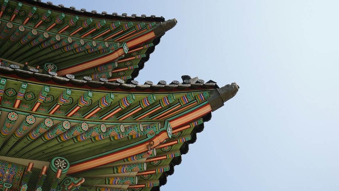 The top of a korean pagoda against a blue sky.